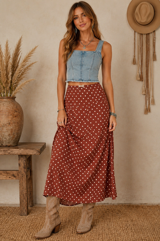 Woman wearing a rust brown maxi skirt with cream polka dots and a flowy silhouette