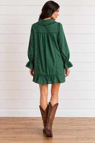 Back view of a forest green mini dress showing a lace-trimmed collar, gathered back, lace accents, and ruffle hem.