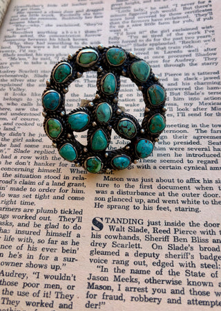 Large peace sign ring featuring multiple natural turquoise stones in shades of blue and green, set in an ornate silver-tone design with a wide band.