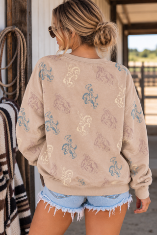 Model wearing Born to Buck tan western sweatshirt with allover bucking bronco and cowboy prin