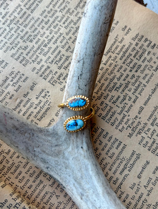 Adjustable gold-plated sterling silver wrap ring with two oval Golden Hills turquoise stones framed by beaded borders, displayed on an antler.