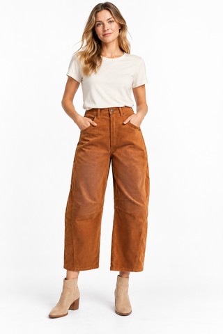 Model wearing rust-brown corduroy barrel pants with a high waist and cropped legs, styled with an ivory tee and beige ankle boots.