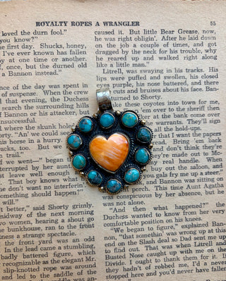 Orange spiny oyster heart pendant surrounded by turquoise stones with detailed Western-style metalwork.