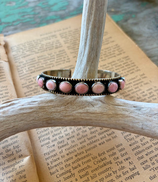 Adjustable silver-tone alloy cuff bracelet with round pink conch accents, an antiqued finish, and beaded edges.