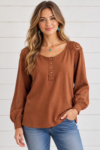 Female model wearing a rust long-sleeve top with crochet shoulder panels and a four-button scoop neckline.