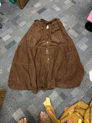 Rust brown corduroy tiered midi dress with button-front detail, tie waist, long sleeves, and a flowy western-inspired silhouette.