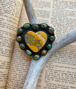 Bumblebee jasper heart ring surrounded by turquoise stones with detailed Western-style metalwork.