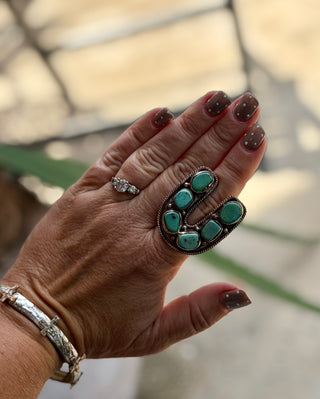 Horseshoe-shaped turquoise ring featuring six natural turquoise stones in an antiqued silver-tone setting with rope detailing.