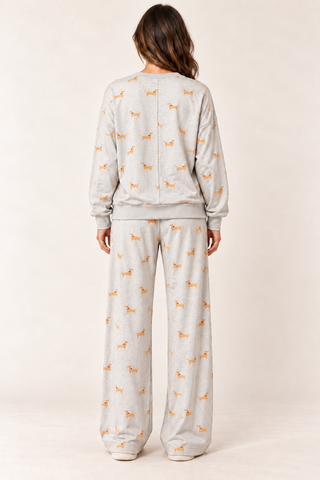 Model wearing the Dachshund Days Lounge Set in heather grey with golden dog print, a long-sleeve crewneck top, and wide-leg drawstring pants.