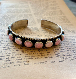 Adjustable silver-tone alloy cuff bracelet with round pink conch accents, an antiqued finish, and beaded edges.