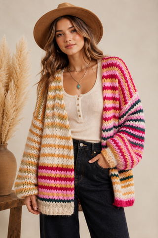Woman wearing a multicolor striped chunky knit cardigan with black pants and a western hat
