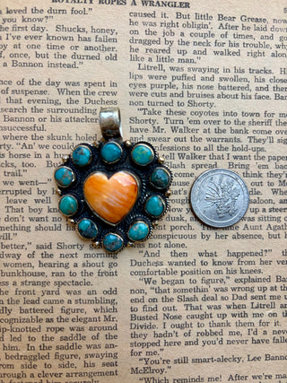 Orange spiny oyster heart pendant surrounded by turquoise stones with detailed Western-style metalwork.