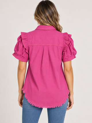 Back view of a magenta ruffle sleeve top with a curved frayed hem, styled with blue jeans.