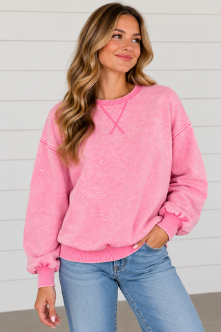 Woman wearing Pink Skies candy pink washed sweatshirt with light wash jeans
