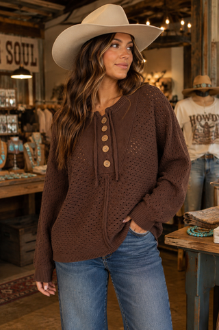 Chocolate brown open-knit pullover sweater with button neckline, tie details, long sleeves, and relaxed fit.