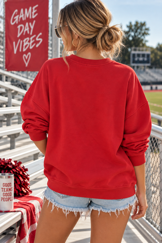 Model wearing red Game Day sweatshirt with white chenille lettering and denim shorts