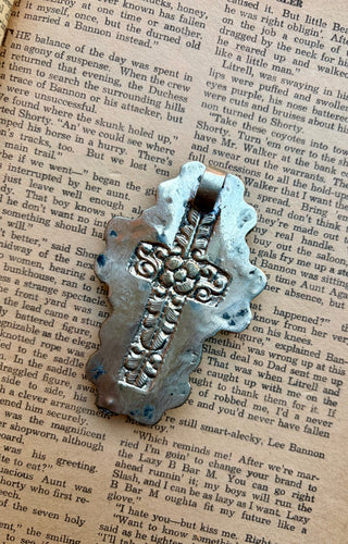 White cross pendant surrounded by turquoise stones with detailed Western-style metalwork.