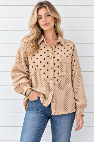 Model wearing a tan gauze button-down shirt with mixed brown polka dots, a chest pocket, and raw-edge panels, styled with jeans.