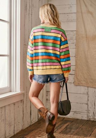 Woman wearing colorful striped sweatshirt with distressed denim shorts and boots