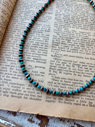 22-inch necklace with alternating Cloud Mountain turquoise beads and copper beads, displayed on an open book.