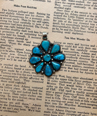 Turquoise cluster pendant featuring multiple teardrop-shaped turquoise stones surrounding a center stone in an antiqued silver-tone setting.