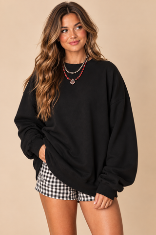 Model wearing black It’s Game Day Y’all oversized sweatshirt with layered red and silver beaded necklaces