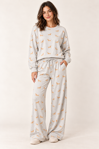 Model wearing the Dachshund Days Lounge Set in heather grey with golden dog print, a long-sleeve crewneck top, and wide-leg drawstring pants.