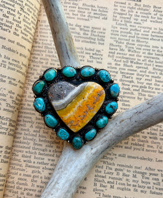 Bumblebee jasper heart ring surrounded by turquoise stones with detailed Western-style metalwork.