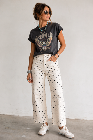 Model wearing ivory high-waisted denim pants with black polka dot print