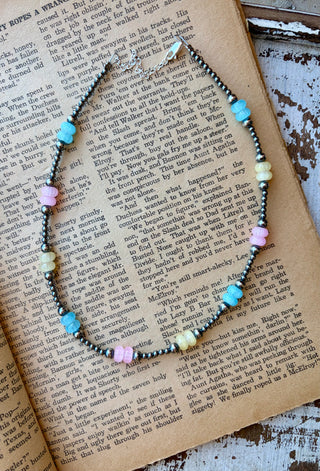 Sterling silver pearl necklace with pastel blue, yellow, and pink glass beads, displayed on an open book.