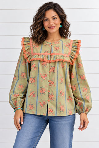 Model wearing a sage green floral blouse with blue stripes, coral lace trim, shoulder ruffles, and balloon sleeves, styled with jeans.