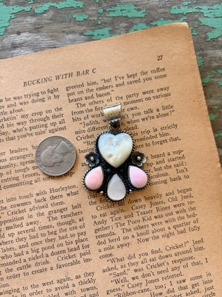 Mother of pearl heart pendant with two pink conch teardrops, a mother of pearl teardrop, and floral details in a silver-tone alloy setting.