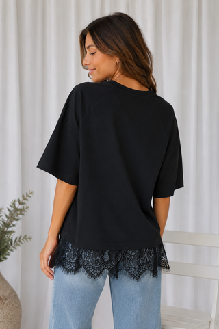Women’s black short sleeve top with floral lace hem on model