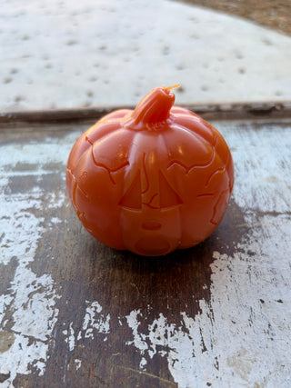 Orange pumpkin squishy with a jack-o’-lantern face and crunchy filling on a distressed wood surface