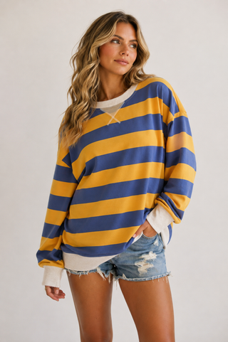 Model wearing blue and golden yellow striped oversized sweatshirt with cream trim