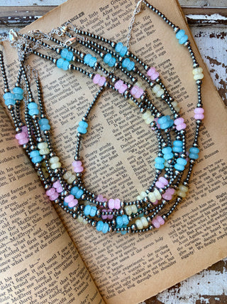 Sterling silver pearl necklace with pastel blue, yellow, and pink glass beads, displayed on an open book.