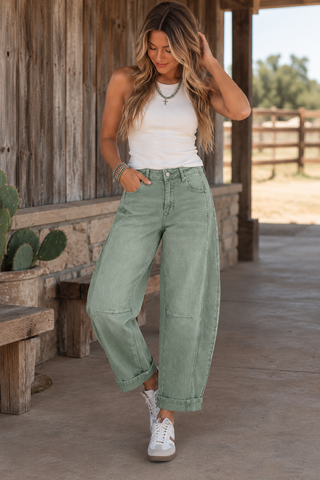 Model wearing sage green high-rise cropped barrel leg jeans with cuffed hems