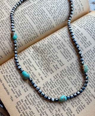 22-inch necklace with 5 mm sterling silver box pearls and authentic turquoise accents displayed on an open book.