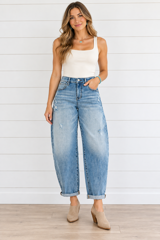 Front view of medium wash Risen barrel jeans with light distressing and rolled ankle cuffs.