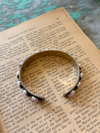 Adjustable silver-tone alloy cuff bracelet with round pink conch accents, an antiqued finish, and beaded edges.