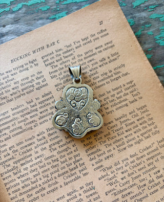 Mother of pearl heart pendant with two pink conch teardrops, a mother of pearl teardrop, and floral details in a silver-tone alloy setting.