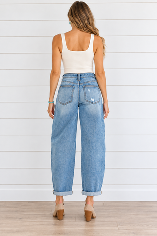 Back view of medium wash Risen barrel jeans with patch pockets, light pocket distressing, and rolled cuffs.