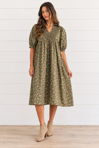 Model wearing a green ditsy floral midi dress with a smocked bodice, collared V-neckline, and puff sleeves.