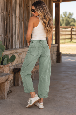 Model wearing sage green high-rise cropped barrel leg jeans with cuffed hems