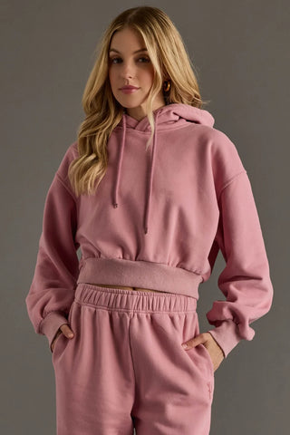 Woman wearing a pink hoodie and pants against a gray background