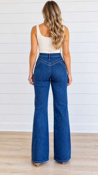 Back view of Risen dark-wash wide-leg jeans showing V-shaped yoke seams, a pocket-free back, and finished hems