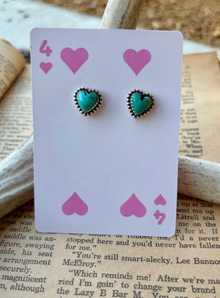 Kelby heart-shaped authentic turquoise stud earrings with beaded sterling silver borders, displayed on a pink heart playing card.