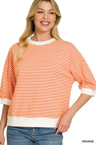 Women’s orange and white striped oversized knit top with a crew neckline, drop shoulders, elbow-length sleeves, and white ribbed trim at the neckline, cuffs, and hem. Relaxed fit with a modern casual style